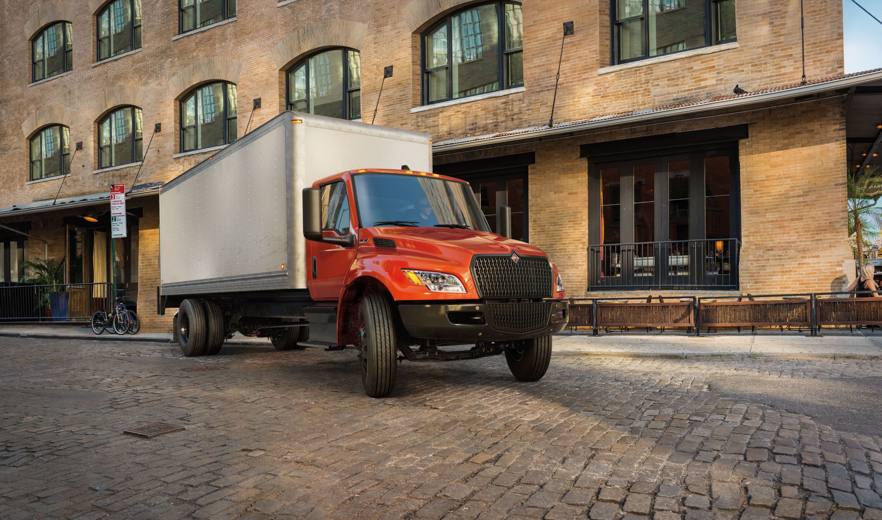 A dark yellow International® Terrastar box truck that's parked next to a building