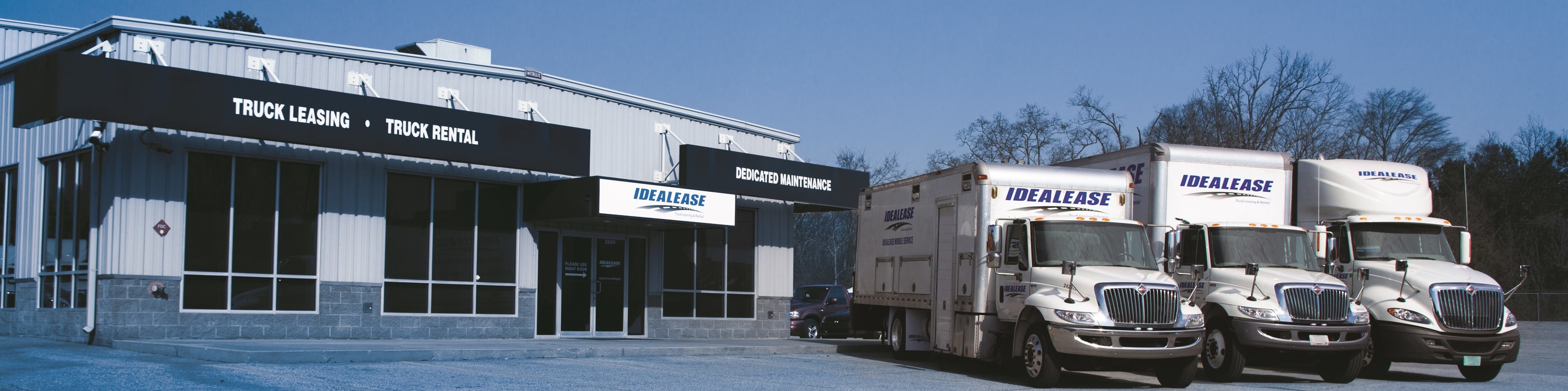 Truck rental storefront with Idealease rental trucks sitting outside.